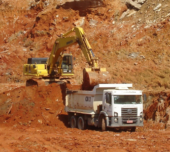 Escavadeira carregando caminhão basculante em obra de terraplenagem da CMX