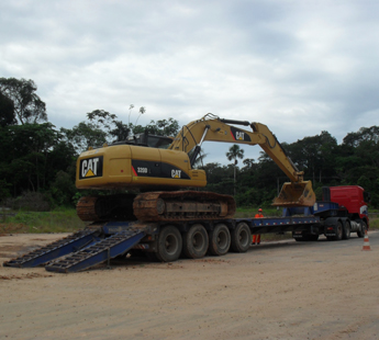 Escavadeira sendo transportada em carreta prancha para obra de mineração